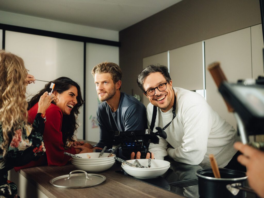 Christian Martin Schäfer laughing with the cast at the kitchen set