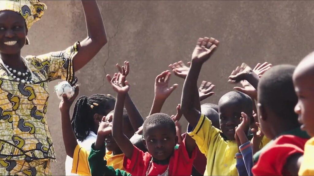 Woman and cheering children stretch their arms into the sun