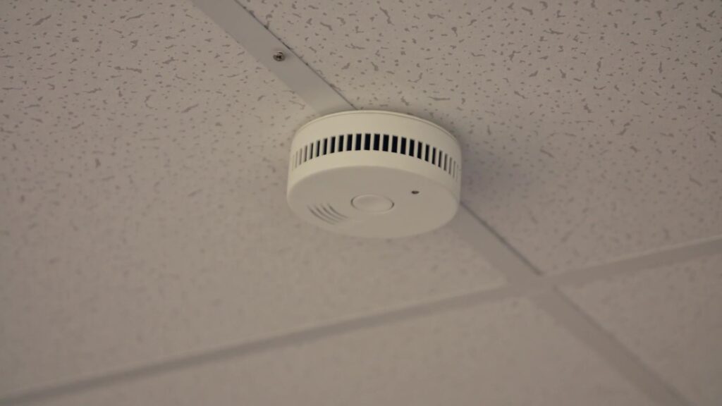 White smoke detector mounted on an office ceiling, close-up