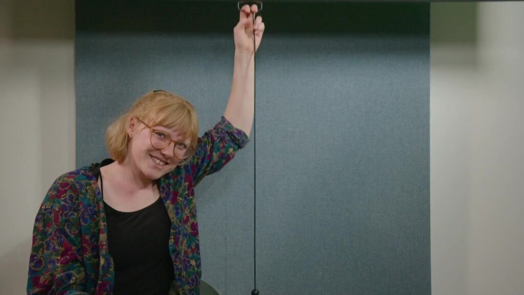 Woman with glasses smiles warmly in the studio room
