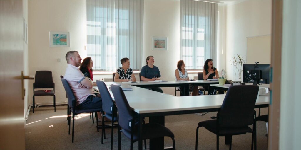 Group of people sit at the table in the bright meeting room