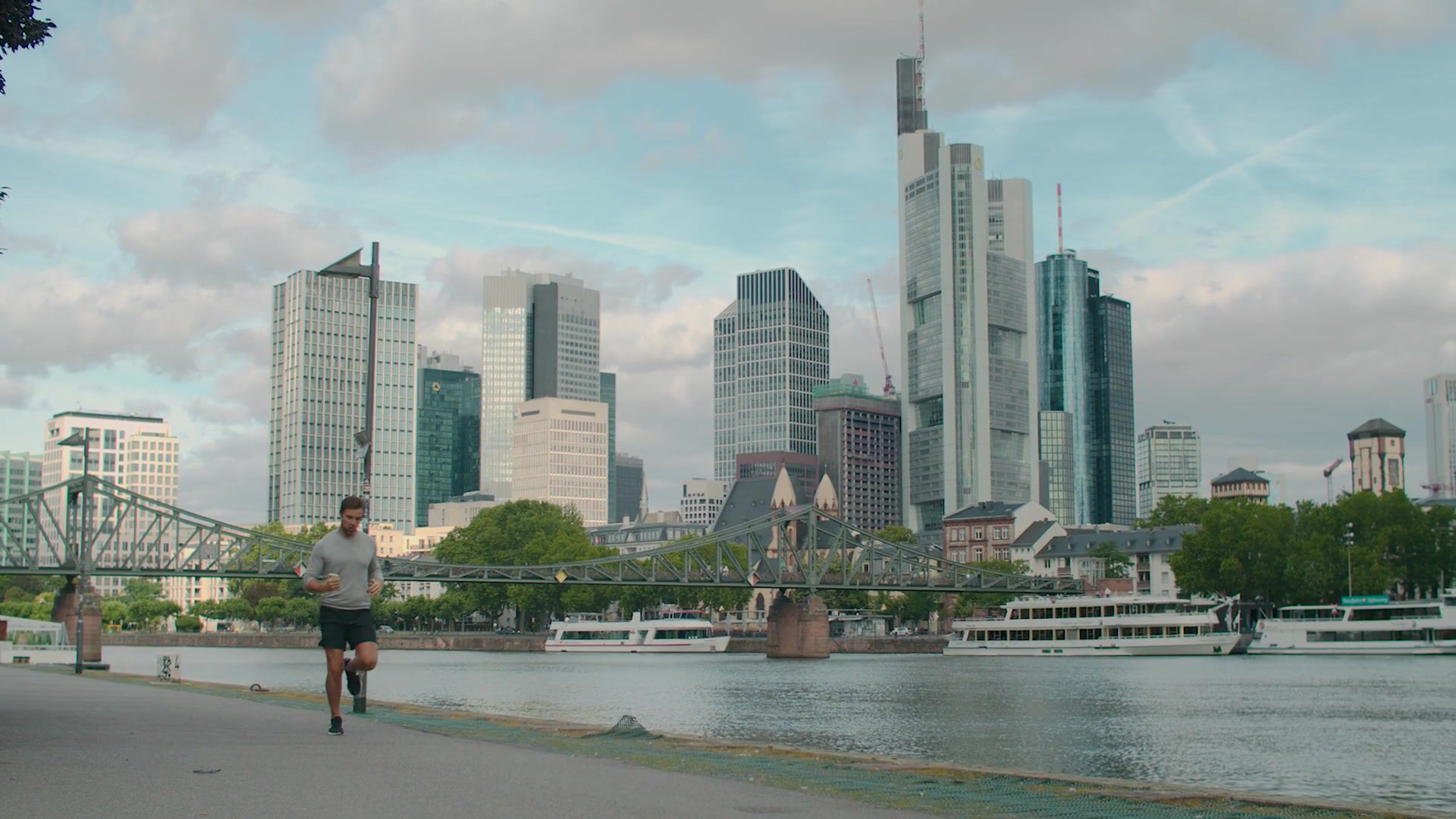 Jogger on the banks of the Main in front of the Frankfurt banking skyline in the morning