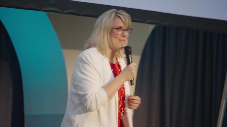 Smiling speaker with a microphone on the event stage