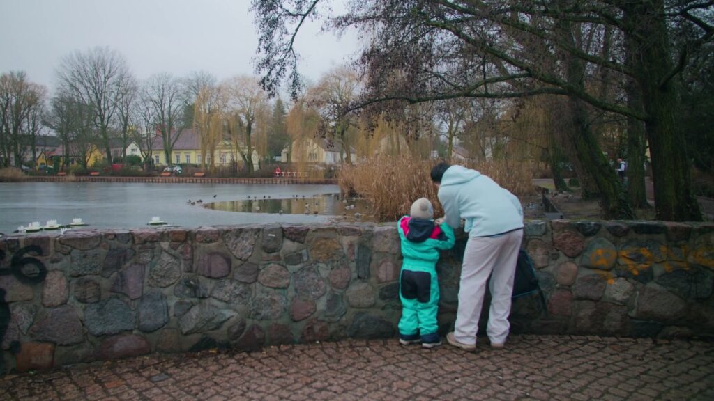 Nancy steht mit ihrem Kind am winterlichen See in Berlin. Szene aus dem Imagefilm der Berliner Jobcenter von ROCC Film.