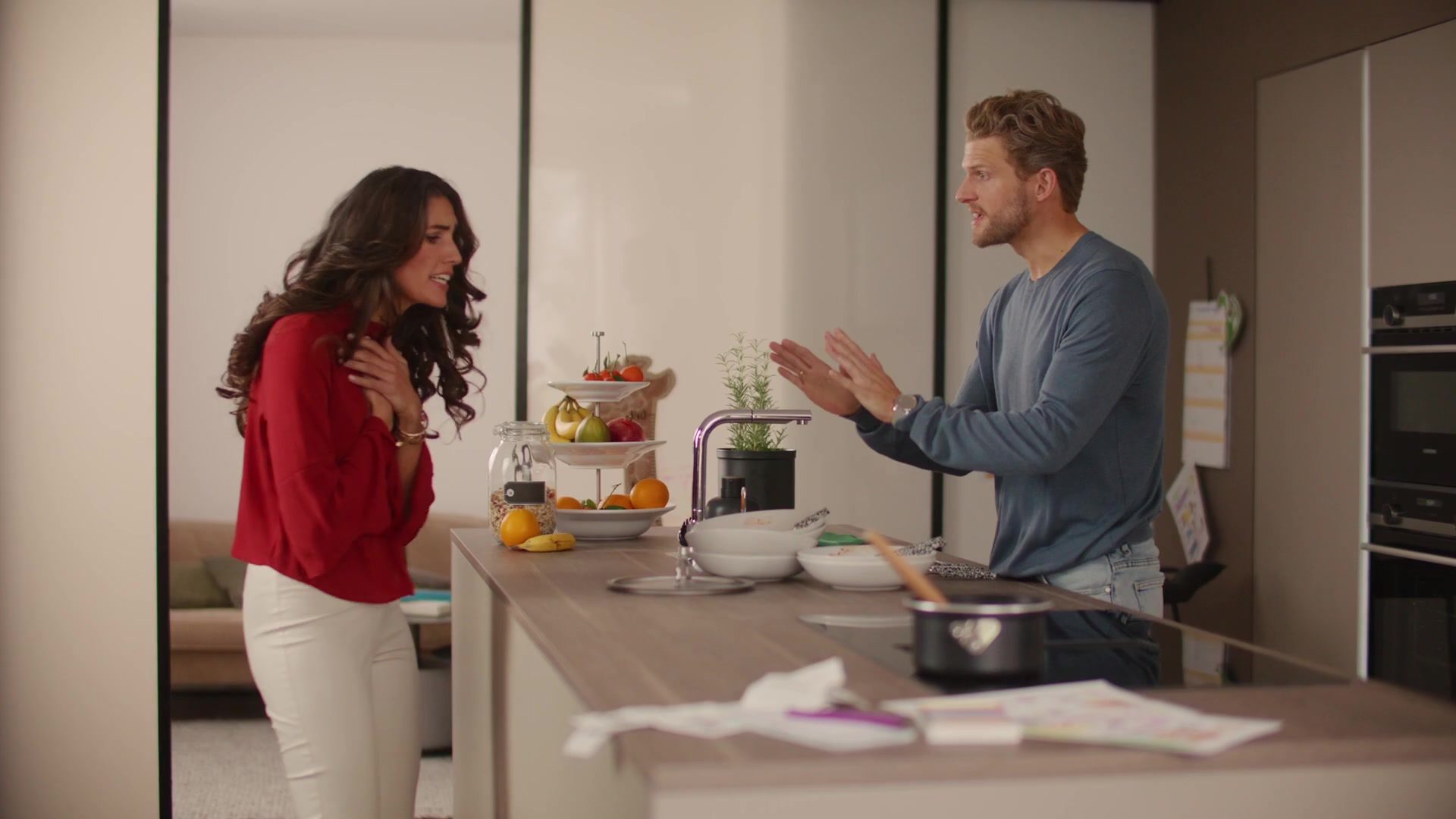 Couple in a modern Nolte eat-in kitchen with a large cooking island and dining area
