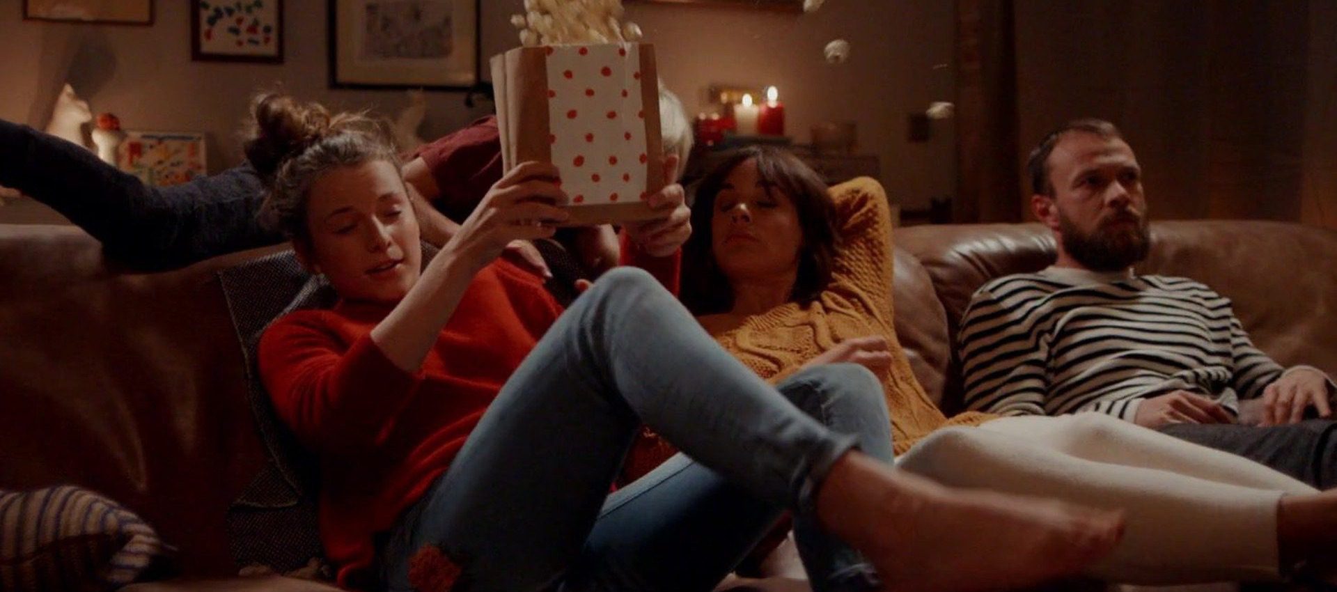 Family enjoys a movie night together with popcorn on the sofa