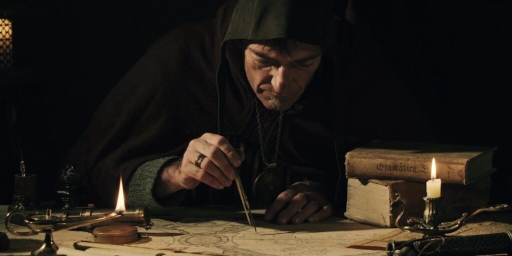 Cartographer draws an old world map by candlelight with a compass