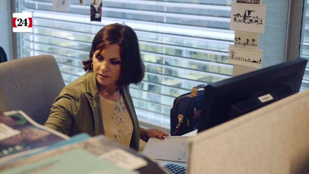 Flavienne reads documents with focus at her workplace in the editorial office