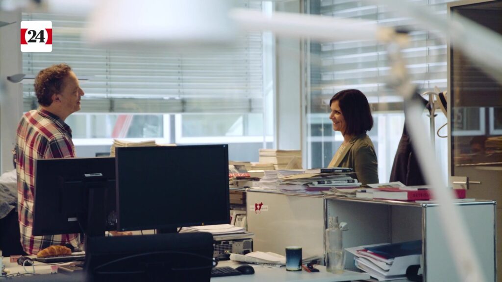 Flavienne laughs while talking to a colleague in the open-plan office