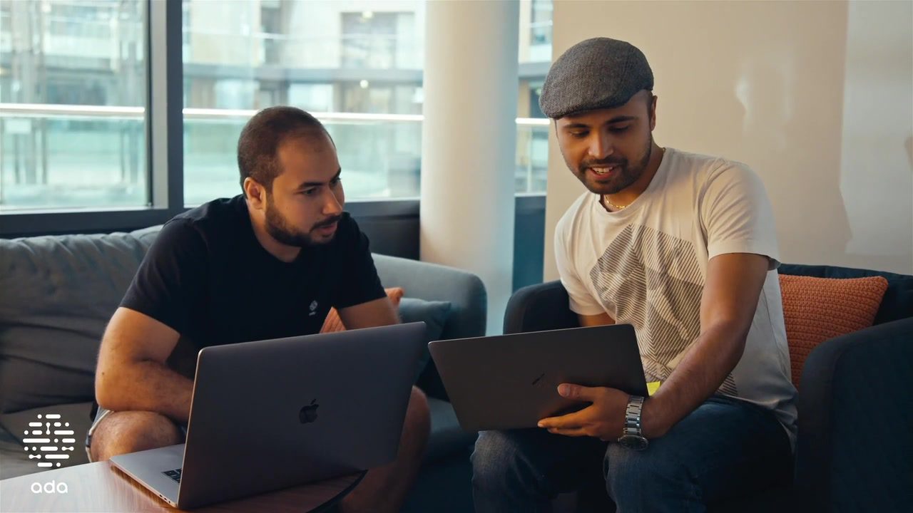 Two colleagues work together on their laptops in Ada Health's office