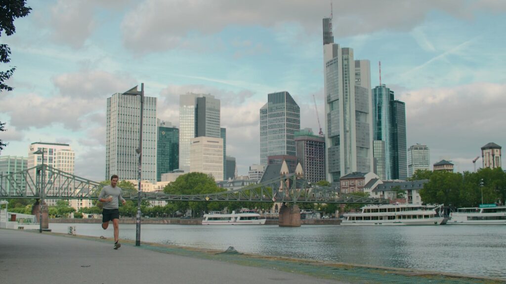 Die Frankfurter Skyline am Main, ein Jogger läuft am Ufer entlang.