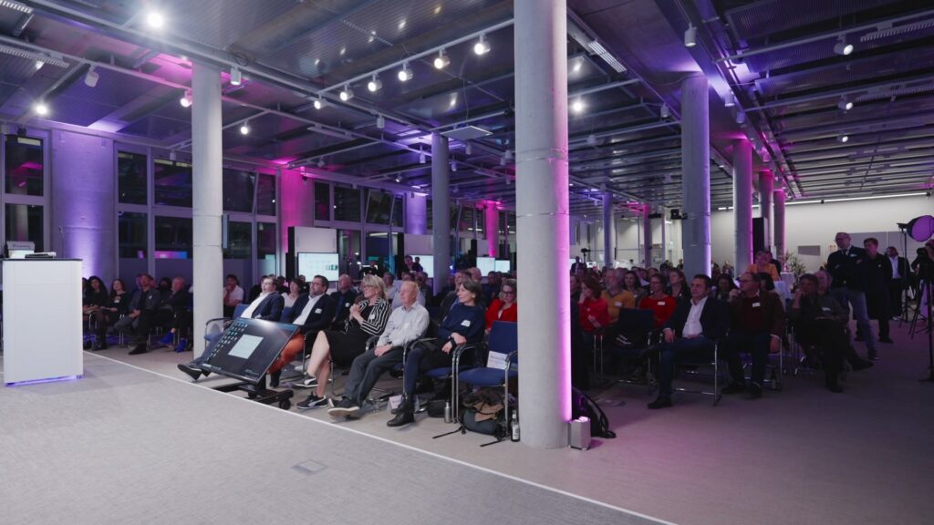 Audience at the DAB Digitalforum 2025 in the purple-lit Forum Digitale Technologien in Berlin