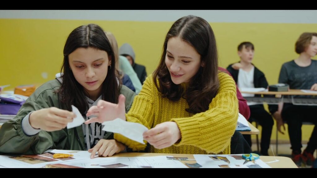 Zwei Schülerinnen gestalten gemeinsam Papierarbeiten im Klassenzimmer