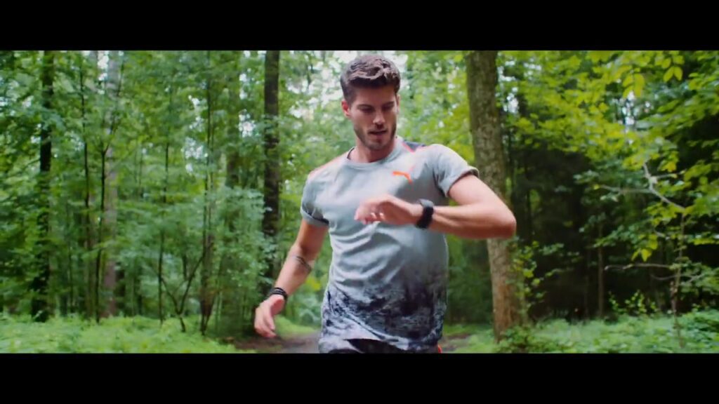 Junger Läufer prüft seine Sportuhr beim Lauf durch den Wald