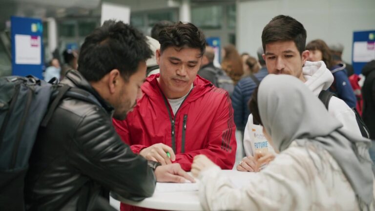 Visitors filling out documents together at a standing table