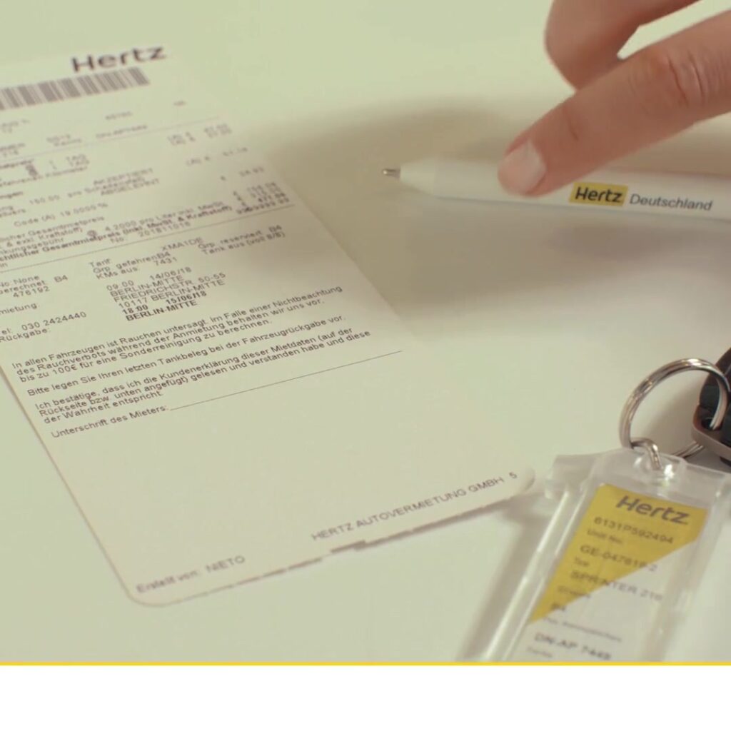 Hertz-Mietvertrag mit Stift und Fahrzeugschlüssel in Nahaufnahme