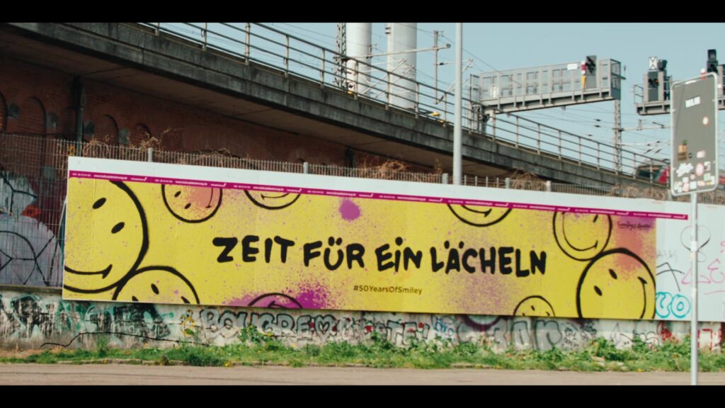 Bunte Smiley-Plakatwand mit dem Schriftzug Zeit für ein Lächeln