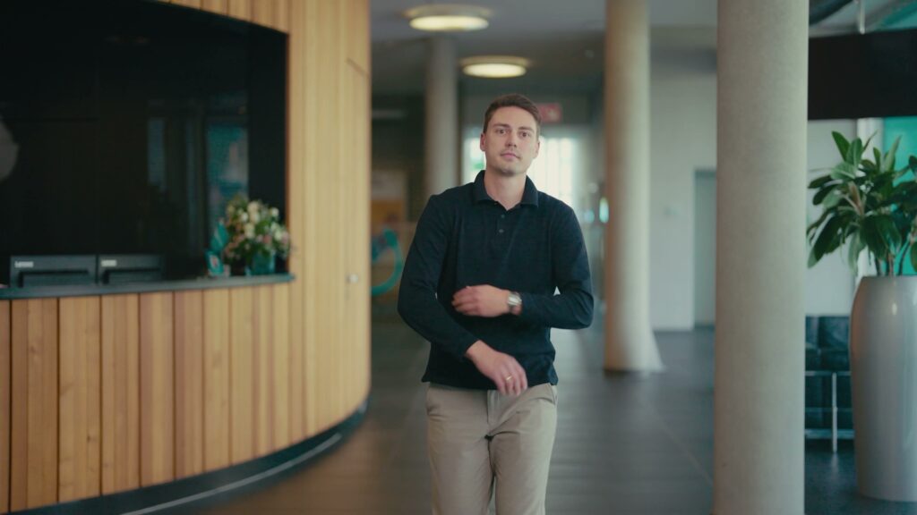 Jan geht durch das helle Foyer von Kenvue in Neuss.