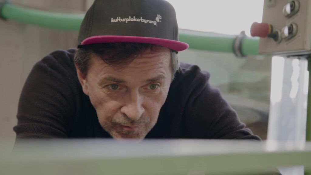 Mitarbeiter mit Kulturplakatierung-Cap arbeitet konzentriert an der Maschine