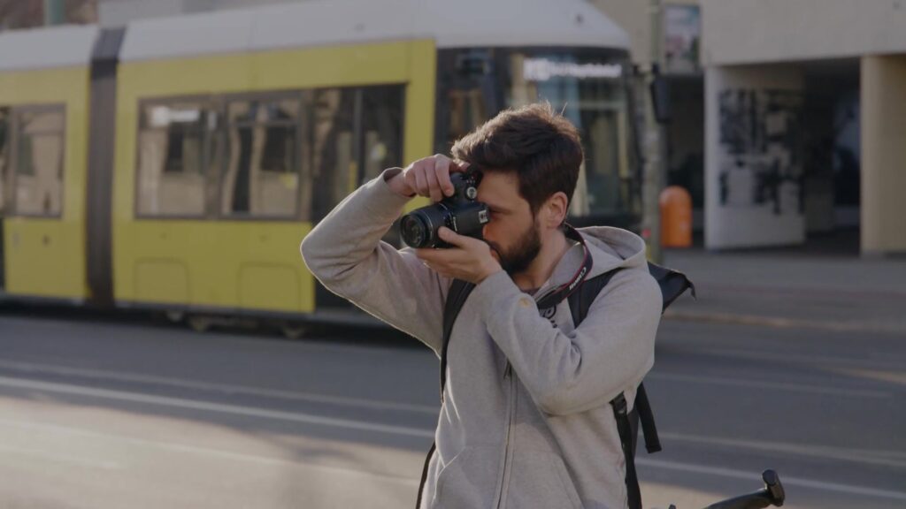 Fotograf fotografiert vor gelber Tram im Berliner Stadtverkehr