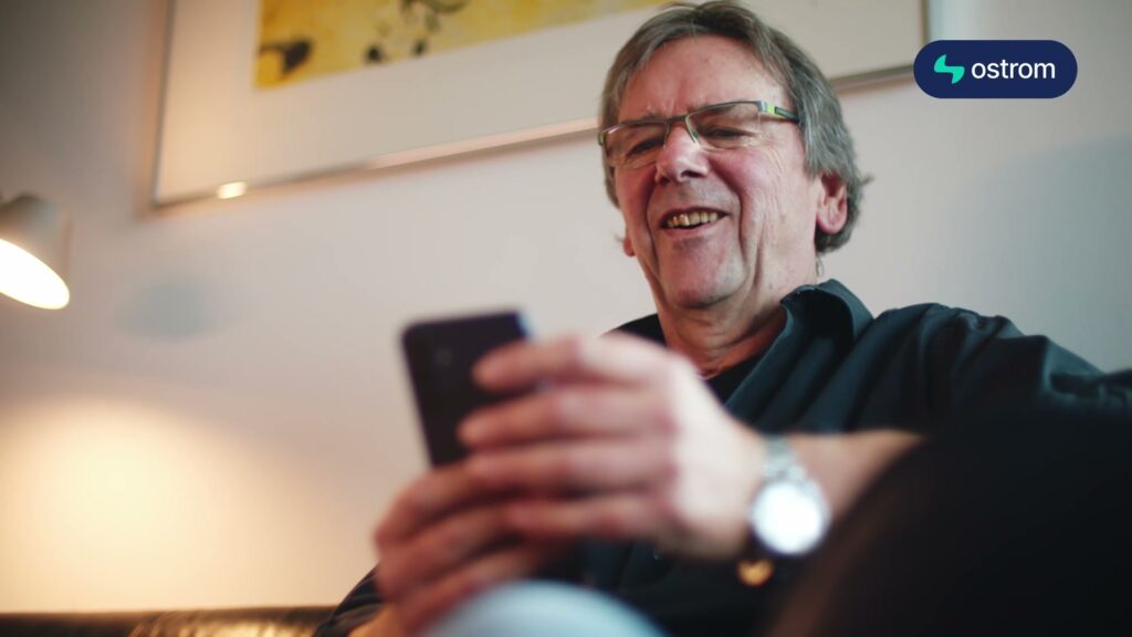 Dieter prüft lächelnd die Ladekosten in der Ostrom-App