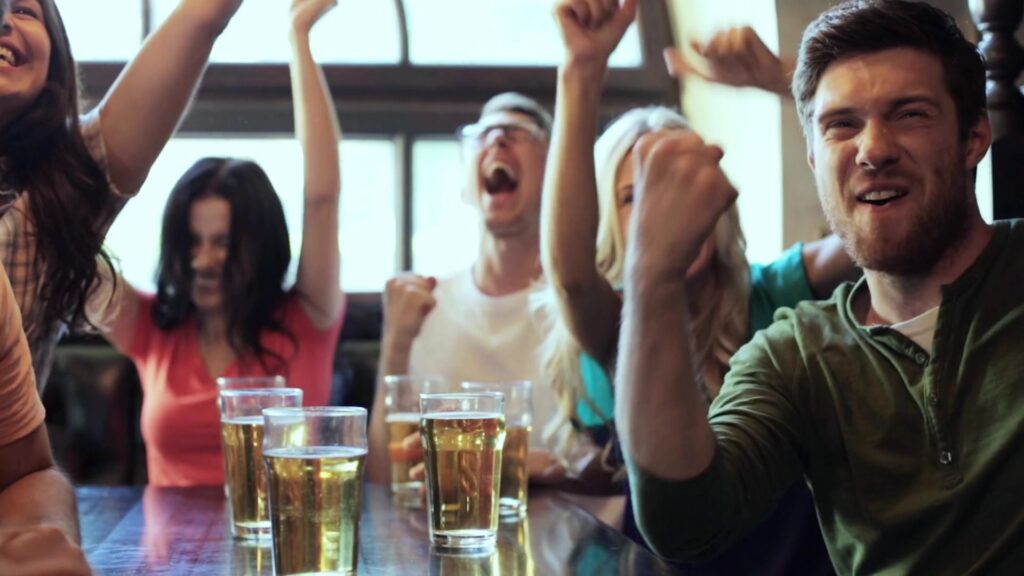 Freunde jubeln mit Bier in der Bar über ein Tor