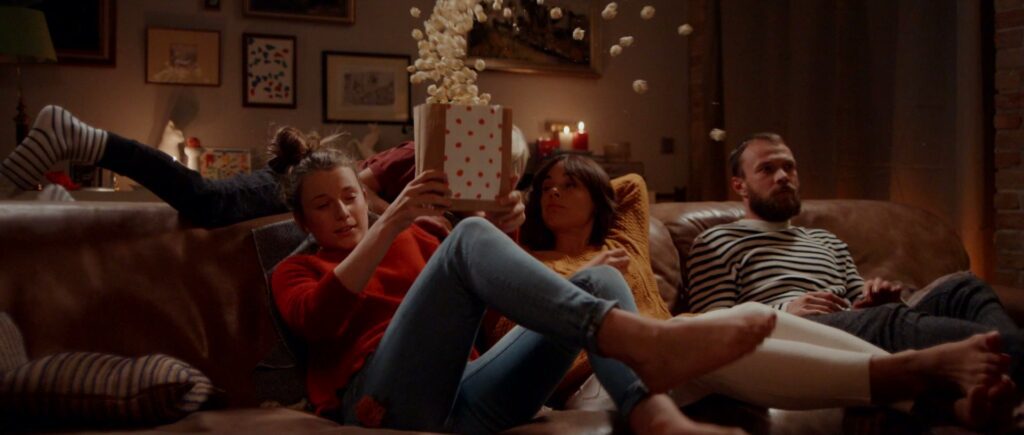 Popcorn fliegt in Zeitlupe über die Familie auf dem Sofa.