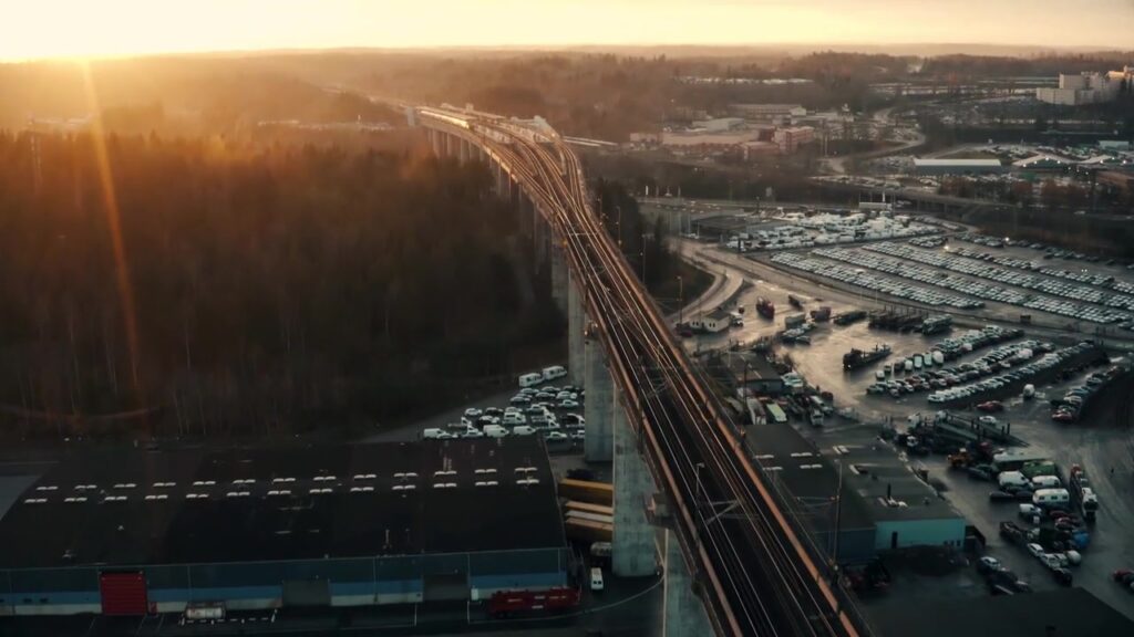 Luftaufnahme einer Bahntrasse und Logistikflächen bei Sonnenaufgang