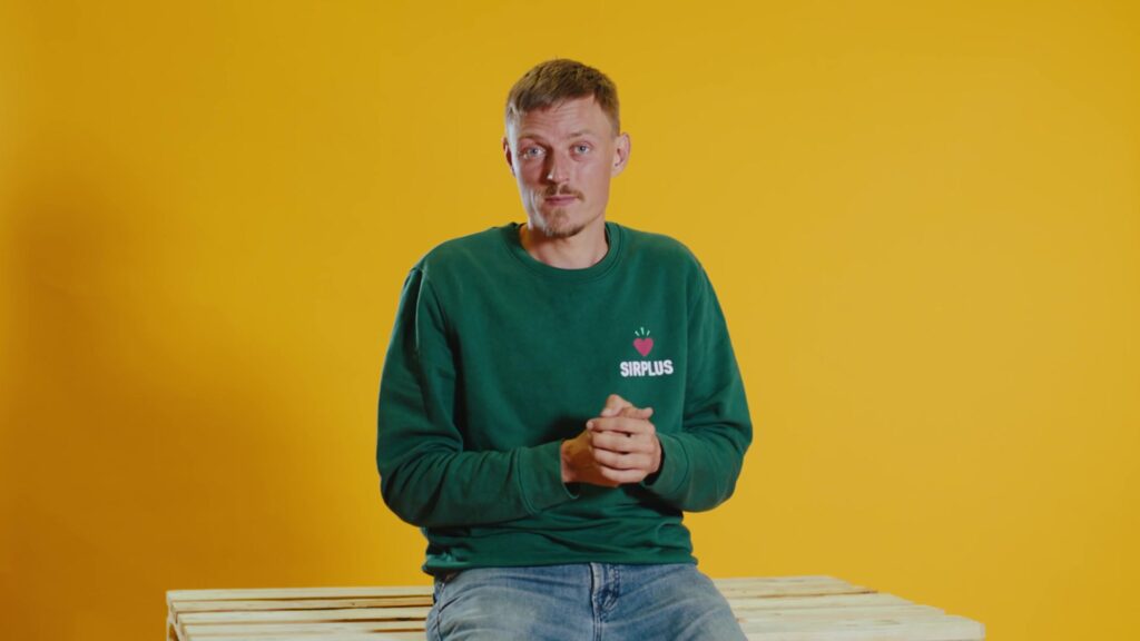 SIRPLUS-Gründer spricht im Interview vor leuchtend gelbem Hintergrund