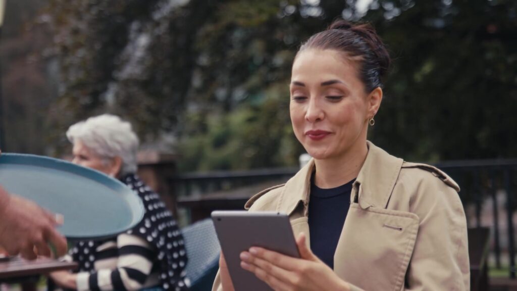 Junge Frau liest lächelnd Nachrichten auf ihrem Tablet