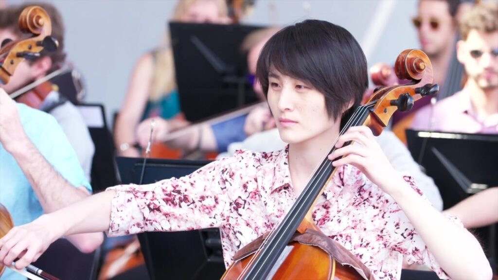 Junge Cellistin spielt konzentriert inmitten des Orchesters