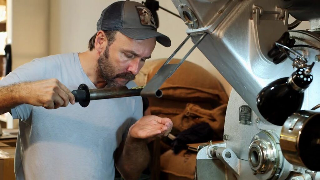 Röstmeister prüft frisch geröstete Kaffeebohnen an der Röstmaschine