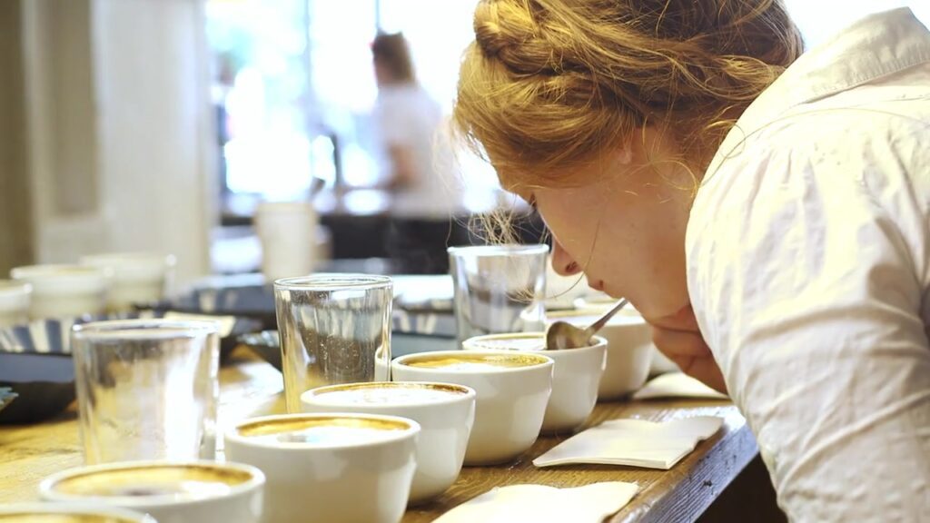Barista verkostet Kaffee beim Cupping mit mehreren Tassen