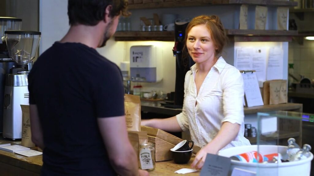 Barista bedient einen Kunden an der Kaffeetheke im Café